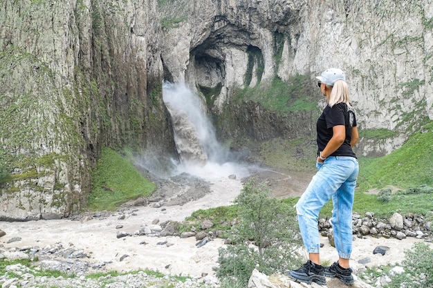 Een meisje op de achtergrond van de TuzlukShapa-waterval op het grondgebied van KabardinoBalkarië Kaukasus Rusland