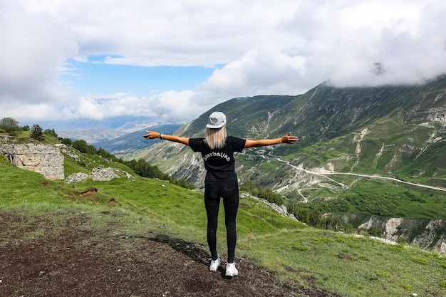 Een meisje op de achtergrond van prachtige groene bergen in Dagestan met wolken Rusland