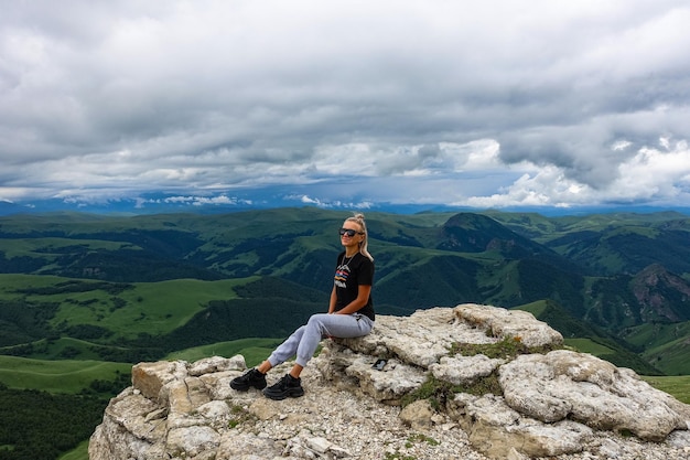 Een meisje op de klif van het plateau tegen de achtergrond van de berg Elbrus Bermamyt