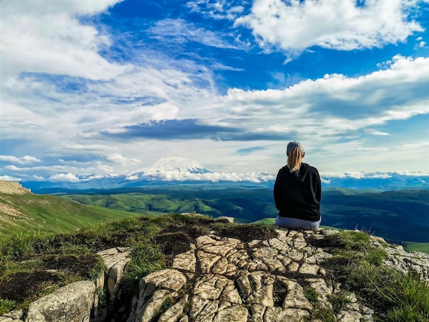 Een meisje op de klif van het plateau tegen de achtergrond van de berg Elbrus Bermamyt