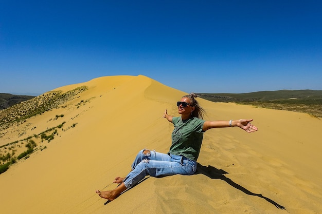 Een meisje op de zandduinen van Sarykum De woestijn in Dagestan, Rusland