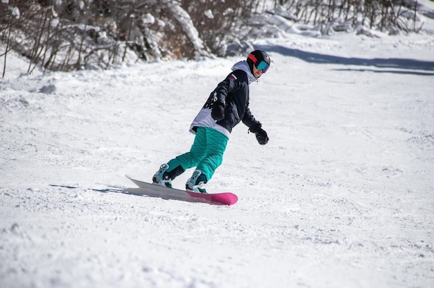 Foto een meisje op een snowboard rijdt langs de berghelling