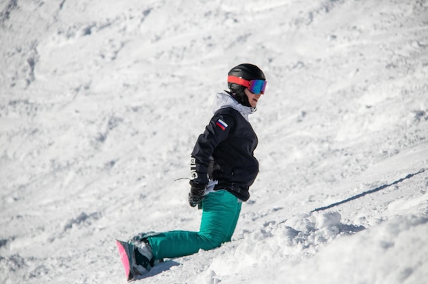 Een meisje op een snowboard rijdt langs de berghelling