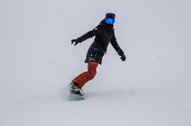 Een meisje op een snowboard rijdt langs de berghelling