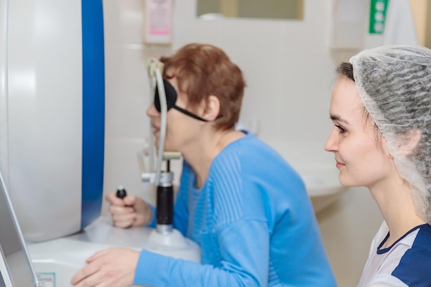 Een meisje-optometrist onderzoekt de ogen van een patiënt met behulp van speciale moderne apparatuur