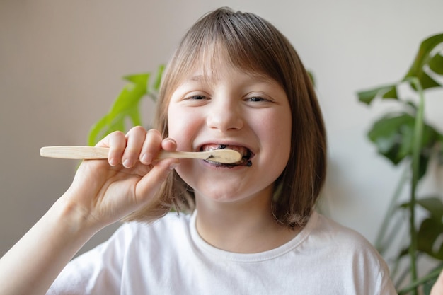 Een meisje poetst haar tanden met een ecologische tandenborstel van bamboe en biologische tandpasta voor mondhygiëne