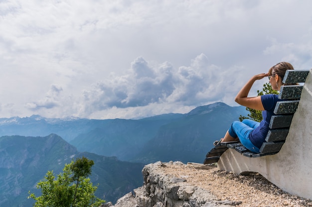 Een meisje rust op de top van een berg zittend op een ongewone bank.