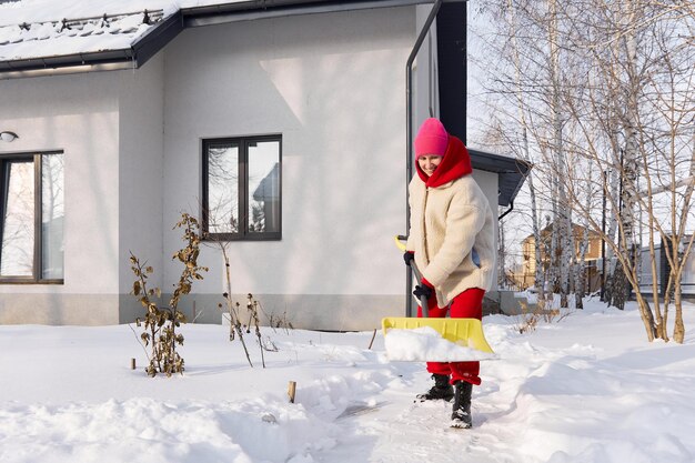Foto een meisje schoonmaakt sneeuw bij het huis gevolgen van sneeuwval