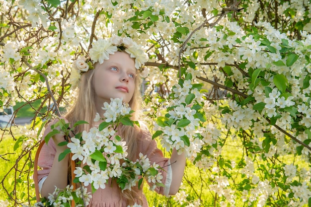 Een meisje snuift een prachtige witte appelboom lente in het midden van de bloei van de appelboom