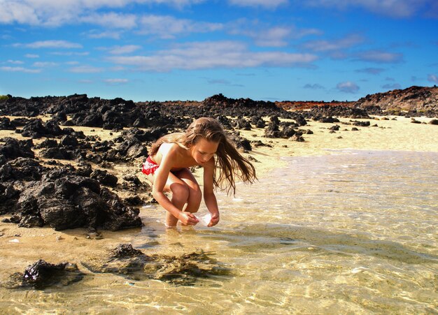 Een meisje van 10 jaar vis en krabben vangen, in het water aan de kust, oceaan