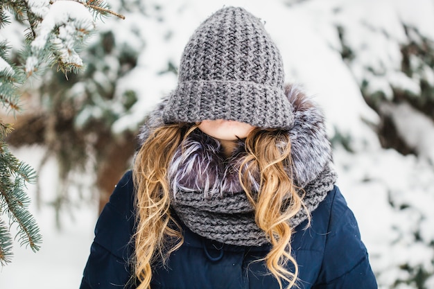 Een meisje van Europese uitstraling loopt in het park, bos, winter en sneeuw, gekleed in warme kleding, hoed, jas, sjaal, rust, wandelen
