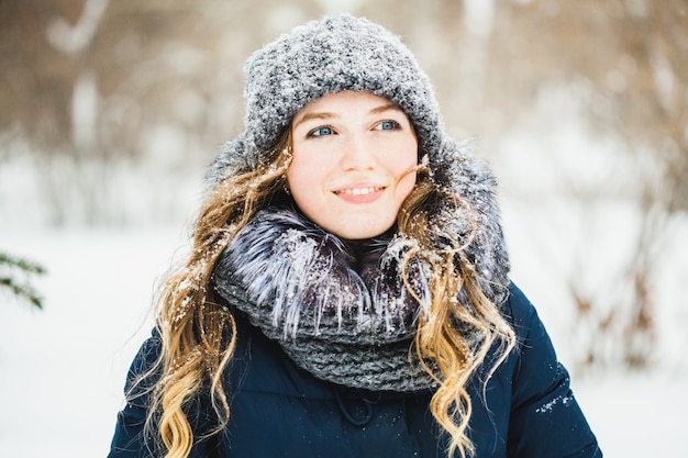 Een meisje van europese uitstraling loopt in het park, bos, winter en sneeuw, gekleed in warme kleding, hoed, jas, sjaal, rust, wandelen