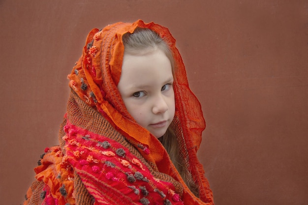 Een meisje van vijf jaar in een rode sjaal. Ze is een beetje verdrietig.