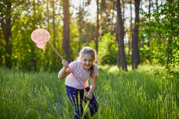 Een meisje vangt vlinders met een roze sapje op een zomerse dag