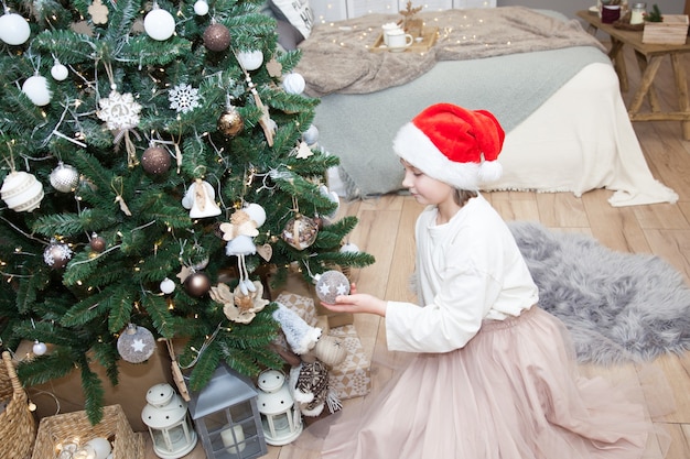 Een meisje versiert een kerstboom in een feestelijke slaapkamer