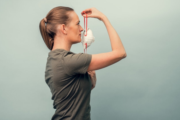 Een meisje zet een beschermend masker op. ademhalingsbescherming tegen coronavirus. persoonlijke beschermingsmiddelen voor een pandemie van een virale infectie. covid-19.