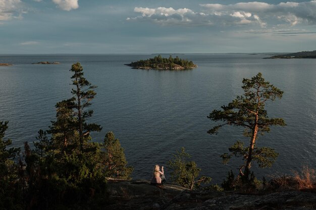 Een meisje zit op de berg van het noordelijke strand van het eiland Kojonsaari aan het Ladoga-meer