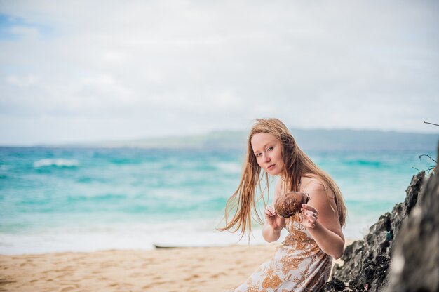 Een meisje zit op een rots op het strand van Boracay