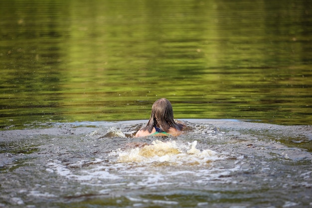 Een meisje zwemt in de rivier op een hete zomerdag