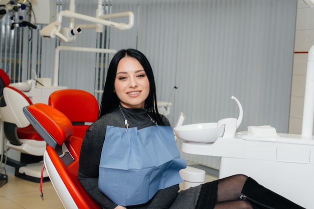 Een meisjespatiënt van een tandheelkundige kliniek zit in een stoel en glimlacht.