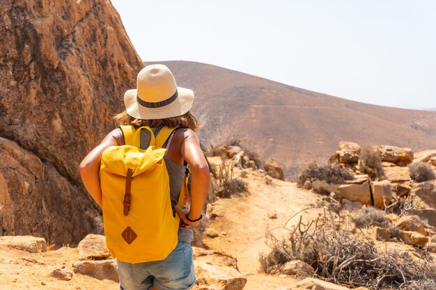 Een meisjeswandelaar met een gele rugzak op het Mirador de la Peñitas-pad in de Peñitas-canyon, Fuerteventura, Canarische Eilanden. Spanje