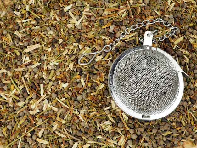 Een mengsel van gedroogd vitexfruit en gedroogd hypericum als achtergrond en zeef voor het zetten van thee