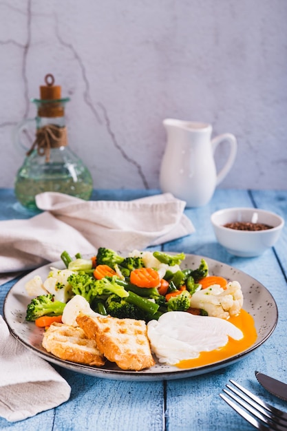 Foto een mengsel van gekookte groenten, gepocheerd ei en toast op een bord op de tafel.