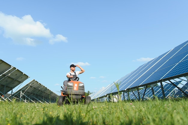 Een mens drijft een grasmaaier dichtbij zonnepanelen Concept zonne-energie