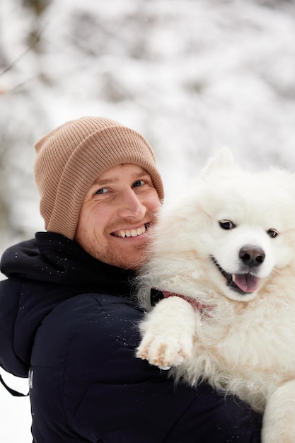 Een mens en een hond zijn beste vrienden Man en hond wandelen in de winter in het besneeuwde bos in diepe sneeuw op een zonnige dag