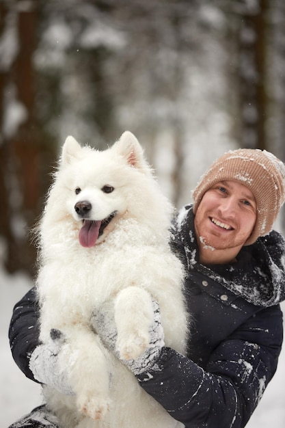 Een mens en een hond zijn beste vrienden Man en hond wandelen in de winter in het besneeuwde bos in diepe sneeuw op een zonnige dag