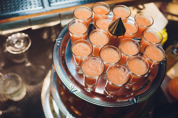 Een metalen zilveren dienblad vol met alle shotglazen wodka, gin en tequila heldere pure alcohol.