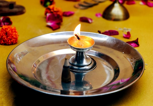 Een metallic zilveren standaard diya of lamp met een brandende pit erin