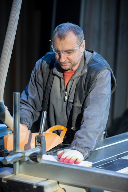 Een meubelmaker bij een snijmachine maakt meubelonderdelen. Fabricage van meubels.