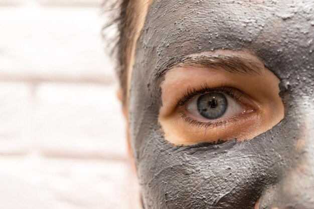 Een middenaanzicht van het gezicht van een vrouw met een zwart cosmetisch masker op