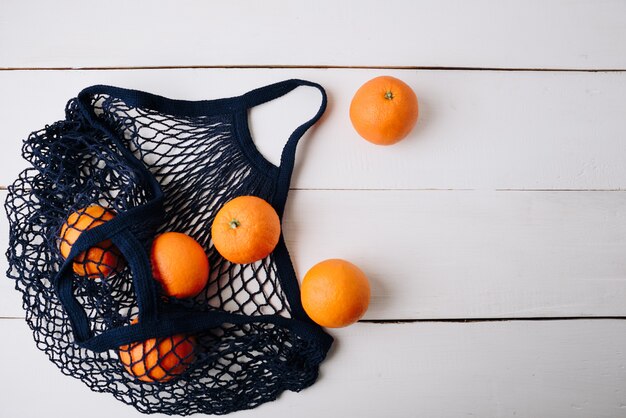 Een milieuvriendelijke tas met sinaasappelen op een houten achtergrond