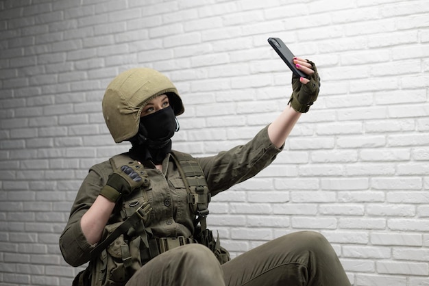 Een militair meisje met een helm maakt een selfie op een mobiele telefoon