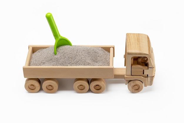 Een miniatuur houten speelgoedkar gevuld met zand met een groene schop erin Leuk voor jongens close-up wit