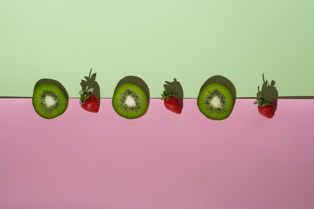 Foto een minimalisme aardbei en kiwi op witte en roze achtergrond