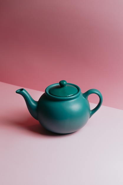 Een minimalistische blauwe theepot op een pastelroze achtergrond met kopie ruimte