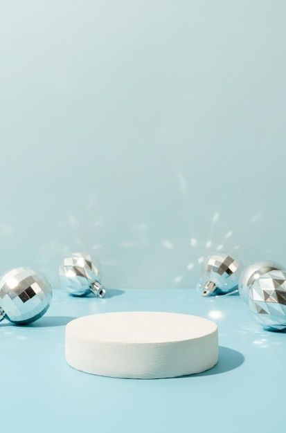 Een minimalistische scène van een podium met decoratieve kerstballen op een lichtblauwe achtergrond