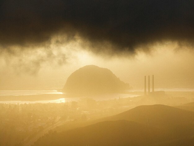 Foto een mistige lucht over een stad met een grote rots in de verte