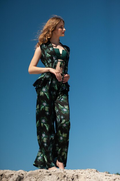 Een model draagt een groene gebloemde jumpsuit met een zwarte top en een zwarte top.