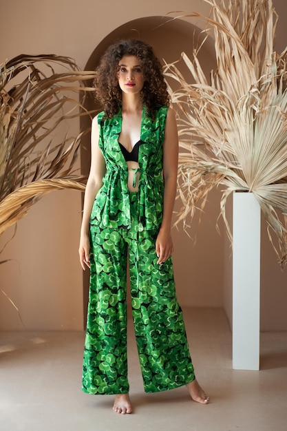 Een model draagt een groene jumpsuit met een zwarte bh en een zwarte bh.