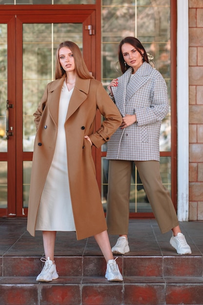 Een modelmeisje dat modieuze bovenkleding toont met een paraplu in haar hand op straat op de veranda van een zomercafé kleding voor de showroom