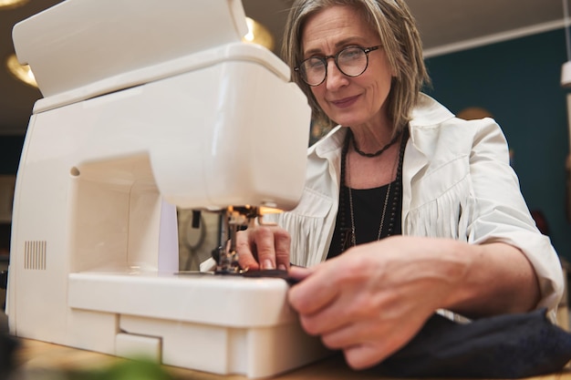 Een modeontwerper die zwarte stof naait op een productienaaimachine in een kleermakersatelier Modeontwerpconcept