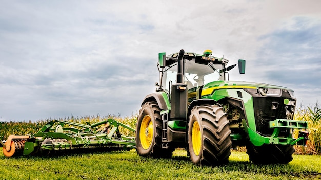 Een moderne groene tractor, maakt landbouwgrond met een ingezaaid veld klaar voor het volgende jaar met behulp van apparatuur en het gebruik van GPS voor precisielandbouw op het land.