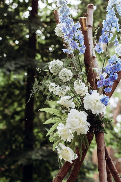 Een moderne huwelijksboog voor een buitenceremonie versierd met witte en blauwe bloemen