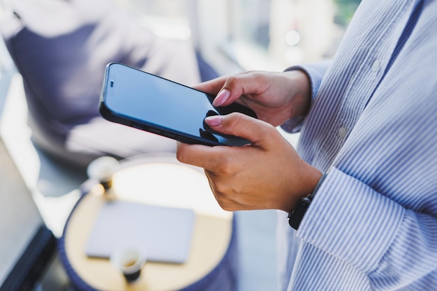 Een moderne mobiele telefoon met een zwart scherm wordt in de handen van een vrouw gehouden, vrouwelijke handen met een smartphone-closeup