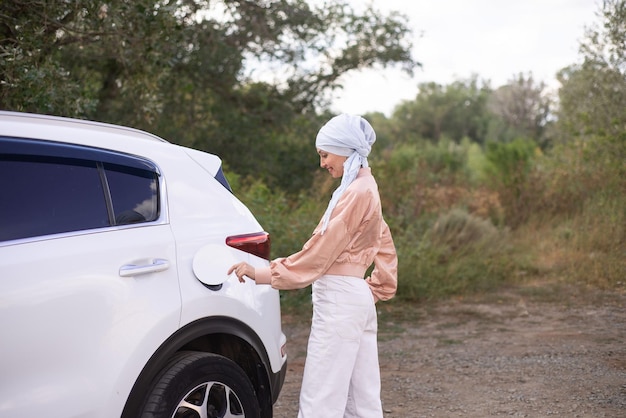 Een moderne moslimvrouw sluit de benzodekking van haar auto