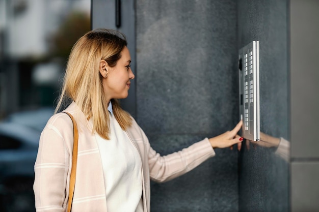 Een modieuze vrouw geeft haar vingerafdruk op de intercom voor het gebouw